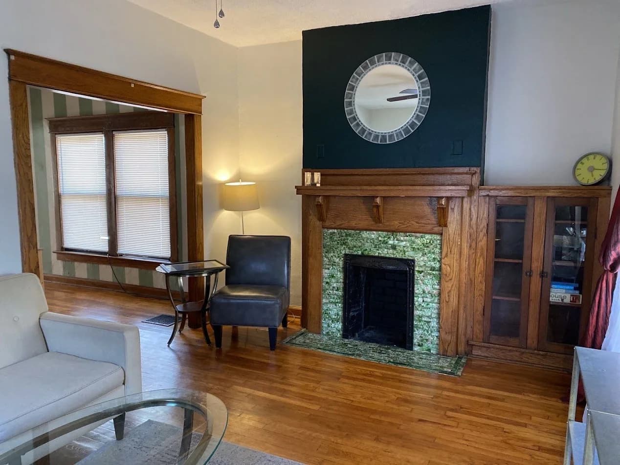Living room with a dark accent wall above a fireplace, light walls, and natural wood trim